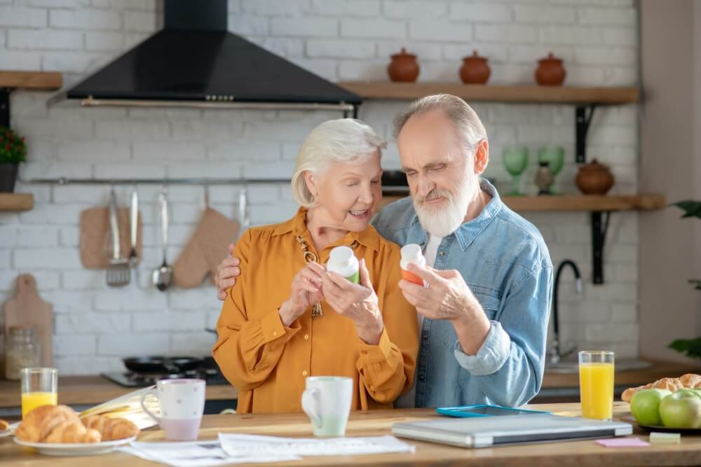 Husband and wife looking at nutritional supplement bottles in their kitchen