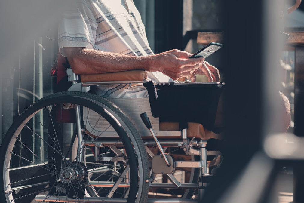 Senior man in a wheelchair looking at a mobile phone